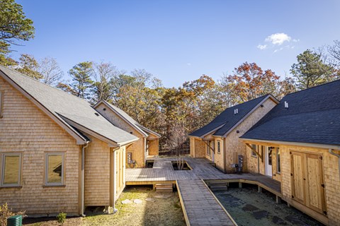 a group of wooden cottages with trees in the background